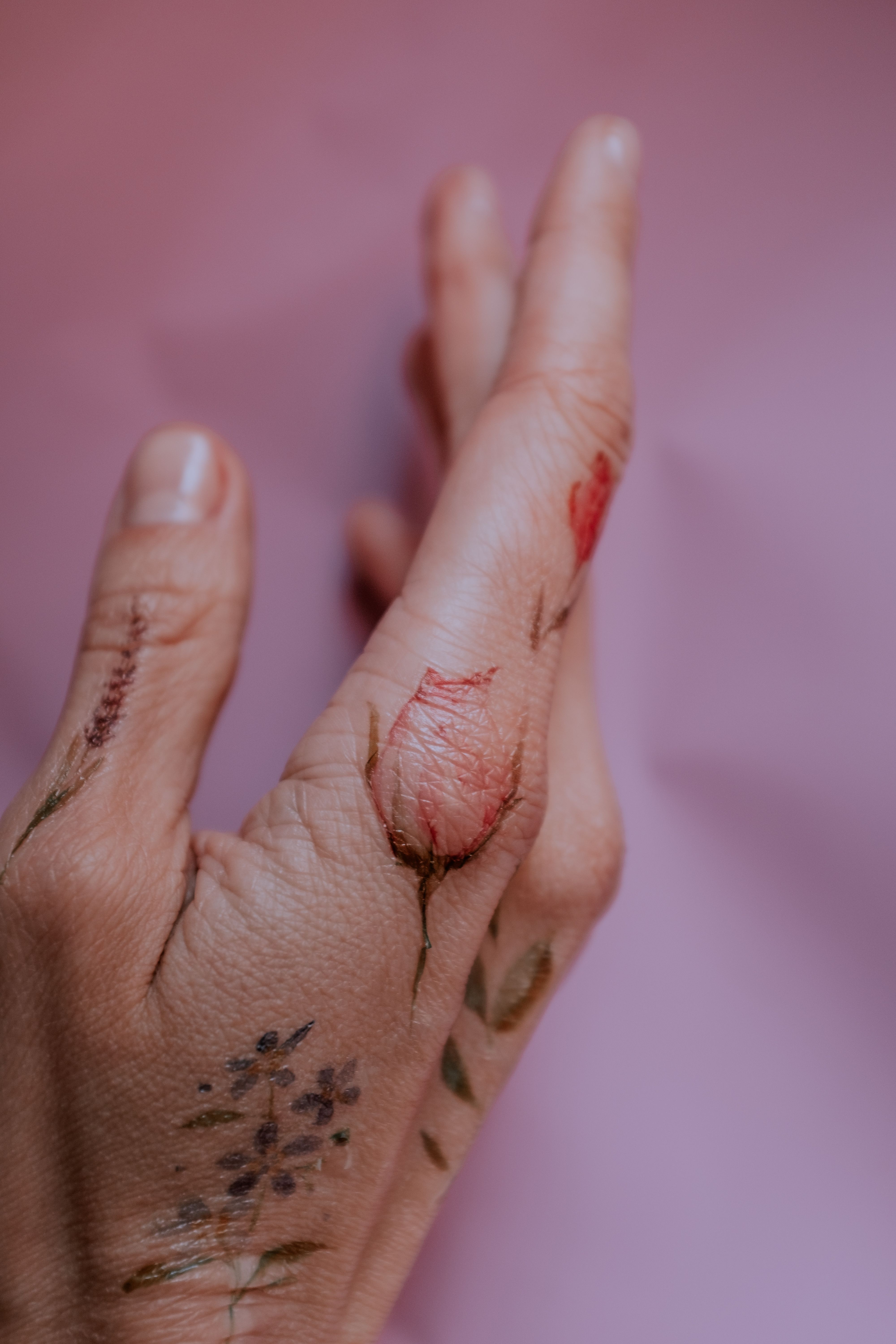 Mão com tatuagens finas nos dedos — flores e detalhes delicados